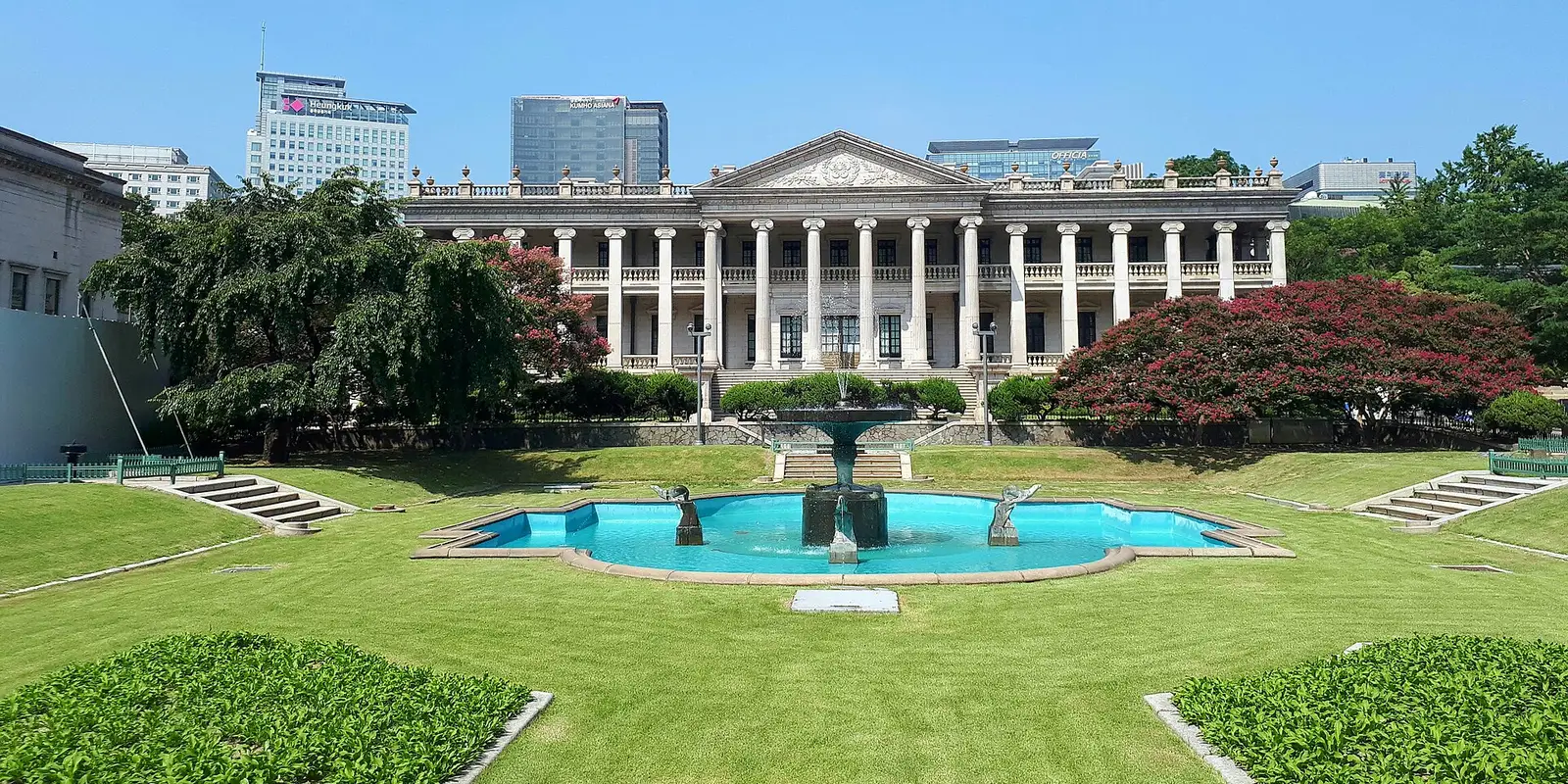 The neoclassical facade of Seokjojeon at Deoksugung, with the fountain in its Western-style garden and Seoul office towers behind