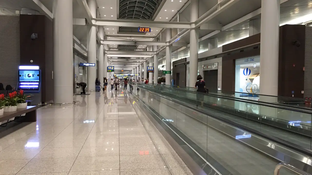 Corridor and moving walkway leading to gates 111 and 112 in the Incheon International Airport concourse, with an overhead clock showing 22:39