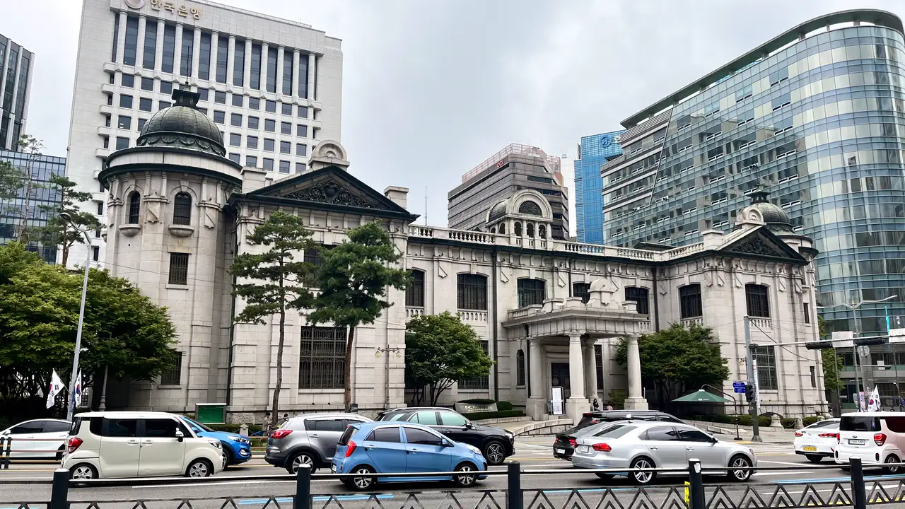 The stone building of the Bank of Korea Money Museum on Namdaemun-ro, Seoul, with the Bank of Korea tower behind it and cars passing in front