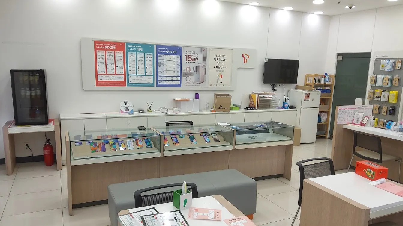 韩国一家SK电讯手机店的店内:白墙上贴着资费海报,玻璃柜台里摆着手机,前面是接待用的桌子